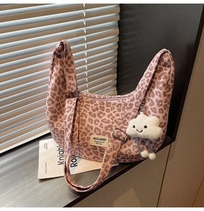 Leopard print crescent tote bag with plush cloud charm and branded label detail