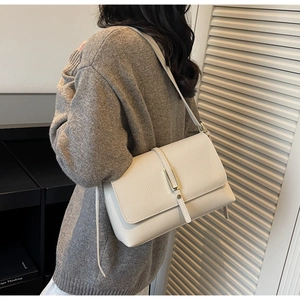 Detail of cream lychee texture leather shoulder bag with light gold buckle on model