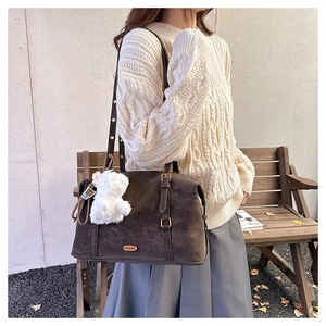 Detailed view of dark brown faux suede tote bag with metal plaque and teddy bear charm