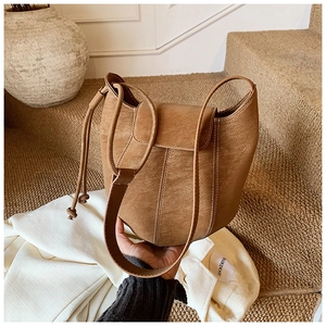Detail of brown leather bucket bag with white contrast stitching and drawstring strap