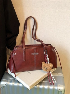 Retro wine red leather tote bag with white stitching and bear charm on white book