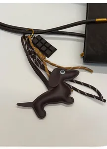 Detail view of dark brown leather dachshund bag charm with chocolate accent and braided cords