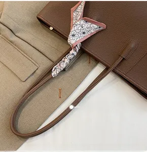 Detail of brown lychee leather tote bag featuring a floral silk scarf on long shoulder strap
