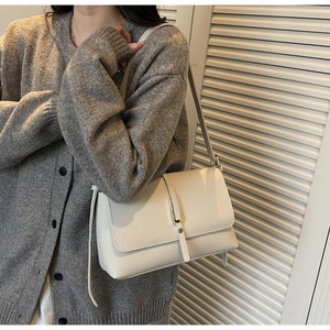 Detail of cream pebbled leather texture and gold buckle on a stylish underarm bag