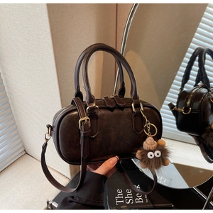 Detail of dark brown leather pillow bag with plush charm and vintage hardware