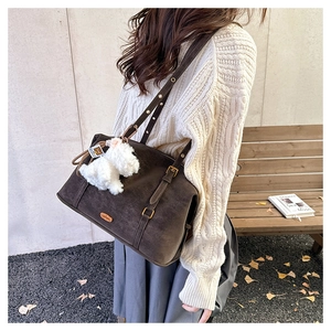 Detail view of coffee suede shoulder bag with gold hardware and plush puppy charm