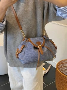 Blue denim and brown leather bucket bag with gold hardware shown on a model