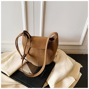 Close-up of brown bucket bag with drawstring and long strap on lifestyle background