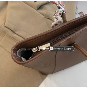 Detailed macro view of smooth golden zipper on a brown pebbled leather tote bag
