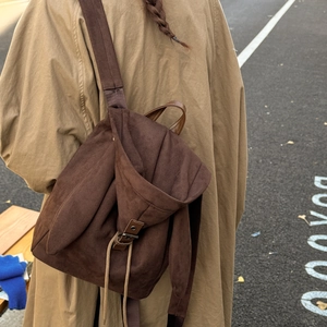 Detail of dark brown suede backpack featuring long rabbit ear decor and drawstring closure
