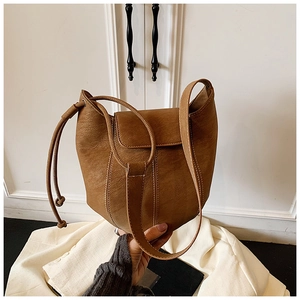 Detail of vintage brown PU leather bucket bag with retro texture and side drawstring