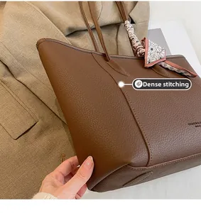 Macro view of fine stitching on brown lychee grain leather tote with floral scarf detail