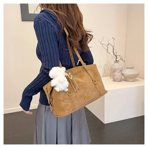 Detail of vintage brown shoulder bag featuring matte texture and plush charm accessory