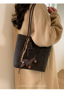 Detail of vintage matte leather tote bag with dachshund charm and braided rope accents