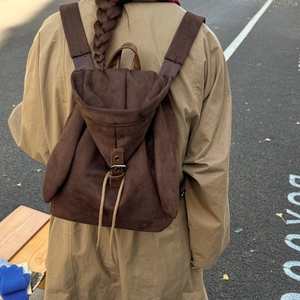 Rear view of a model wearing the brown suede rabbit-ear backpack on an asphalt street