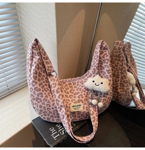 Detail of hobo canvas bag with leopard print, brand label and plush cloud pendant