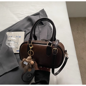 Close-up of retro brown Boston bag with fuzzy charm on professional office setting