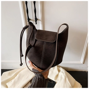 Detail of dark brown retro bucket bag with white contrast stitching and drawstring accent