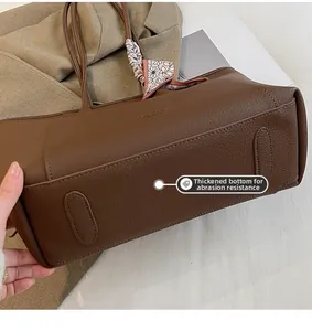 Detail view of thickened wear-resistant bottom on dark brown lychee leather tote bag