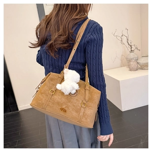 Detailed view of brown matte tote bag with adjustable strap and plush bear charm decoration