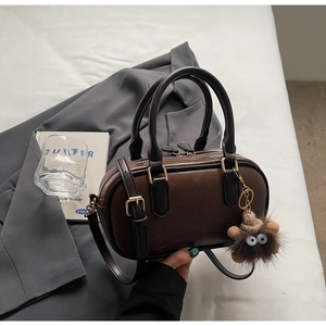Detail of dark brown leather bowling bag with vintage gold hardware and plush lion charm