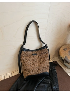 Detailed view of leopard print bucket bag with black leather trim and rubber logo patch