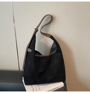 Detail of matte black suede hobo bag featuring adjustable brown leather shoulder strap