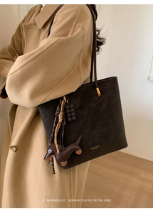 Detail view of black textured leather tote with cute dachshund pendant and gold hardware