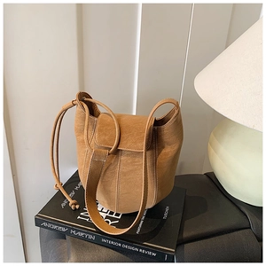 Detail of camel bucket bag showing textured synthetic leather and white contrast stitching