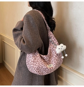Detail of pink leopard crescent bag with a white cloud charm and brand label