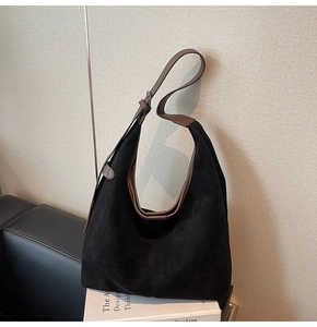 Detail of adjustable brown leather shoulder strap on a black matte tote bag