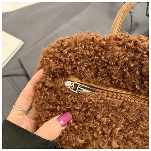 Close-up of brown faux shearling bucket bag with leather trim and smooth metal zipper