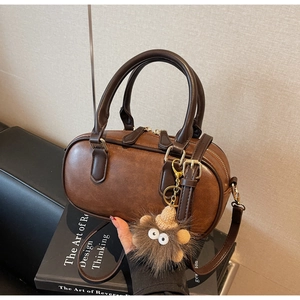 Brown retro Boston bag with plush hedgehog charm on vintage books background