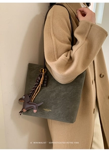 Detail of vintage matte green bucket bag with gold lettering and dachshund dog charm