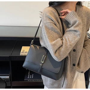 Close-up of black lychee grain leather shoulder bag with elegant gold metal buckle detail