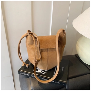 Detailed view of camel leather bucket bag with drawstring resting on art books