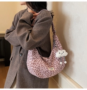 Pink leopard print crescent tote bag with cute cloud charm shown on shoulder with blazer