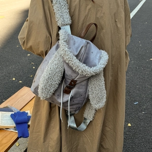 Detail of grey canvas backpack with plush rabbit ears and fleece-covered shoulder straps