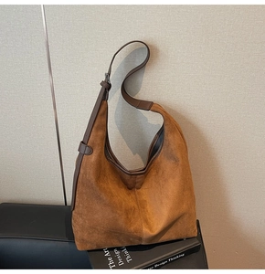 Close-up of brown suede hobo bag with adjustable leather strap and silver metal buckle