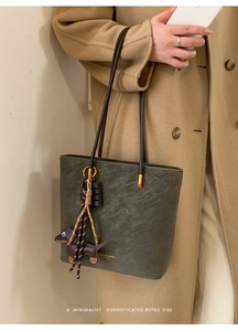Green vintage leather tote bag worn with a camel coat and dachshund charm detail