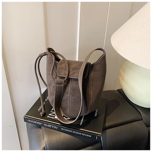 Detail of dark brown bucket bag featuring lychee texture and bold white stitching