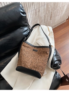 Detail of leopard print bucket bag on black leather sofa with polished black accents