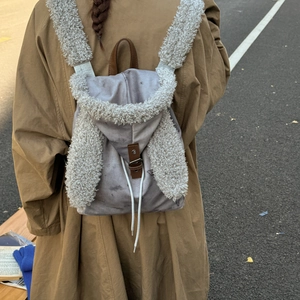 Detail showing plush rabbit ears and soft shearling texture on grey canvas backpack