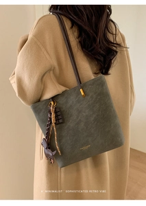 Detail of olive green suede tote bag with dog charm and vintage metal hardware