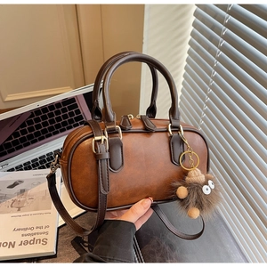 Detail of vintage brown faux leather Boston bag with plush hedgehog charm accessory