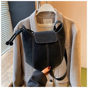 Detail view of black bucket bag with white contrast stitching and side drawstring