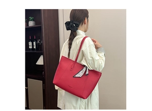 Red pebbled leather tote bag with silk scarf detail shown on shoulder of a model