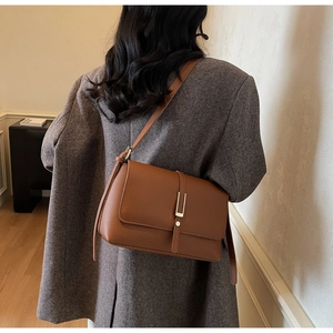 Brown litchi grain leather texture on a vintage underarm bag worn with a grey blazer