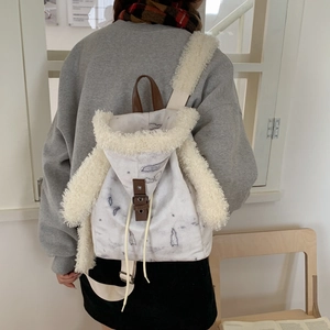 Detail view of canvas backpack with plush trim and drawstring shown on a model's back