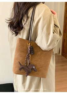 Detail of caramel suede tote bag with cute chocolate and dachshund charms on model